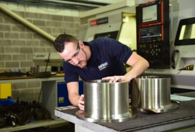 cnc turned parts with person checking their quality leaned to one side