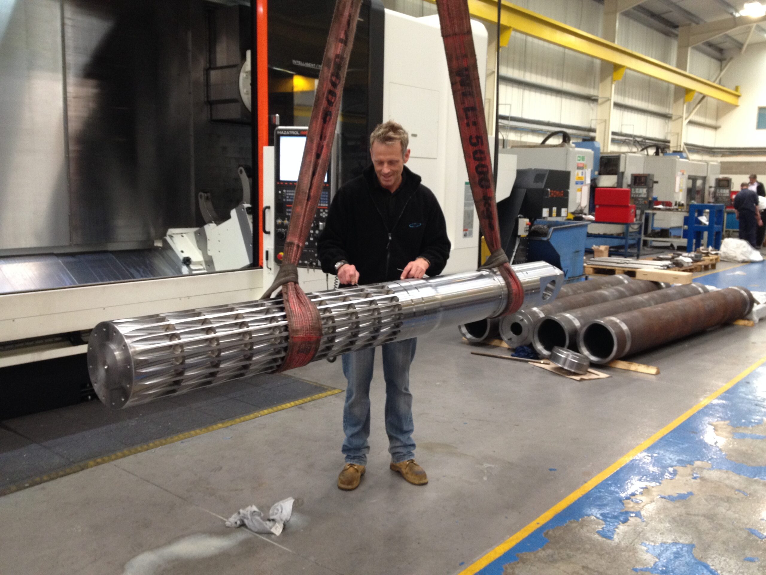 warehouse worker lifting machined part with equipment