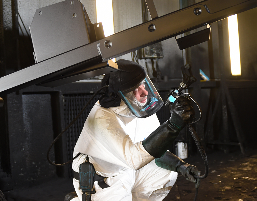 person powder coating a metal part